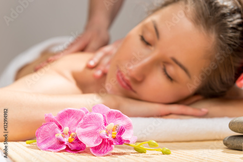 orchid on a massage table in the spa cabinet and a woman's face
