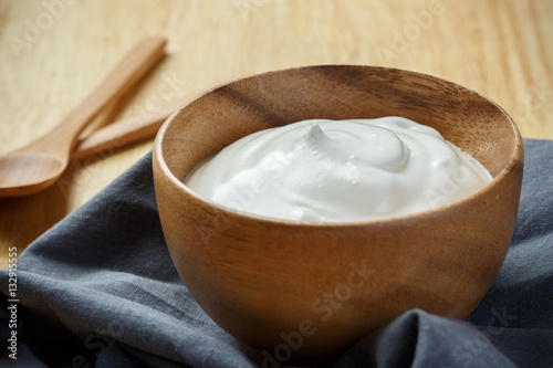 Yogurt in wooden bowl on wooden background with blue cotton and