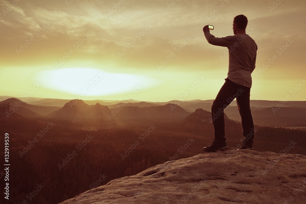 Hiker hold in hand phone and take photo of misty landscape. Hiker hold in hand phone and take photo of misty landscape.