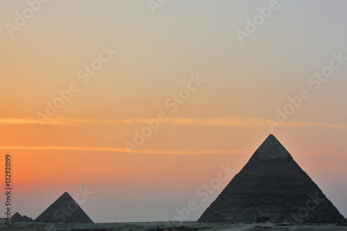 Dramatic sunset behind distant Egyptian pyramids in Giza  Cairo  Egypt