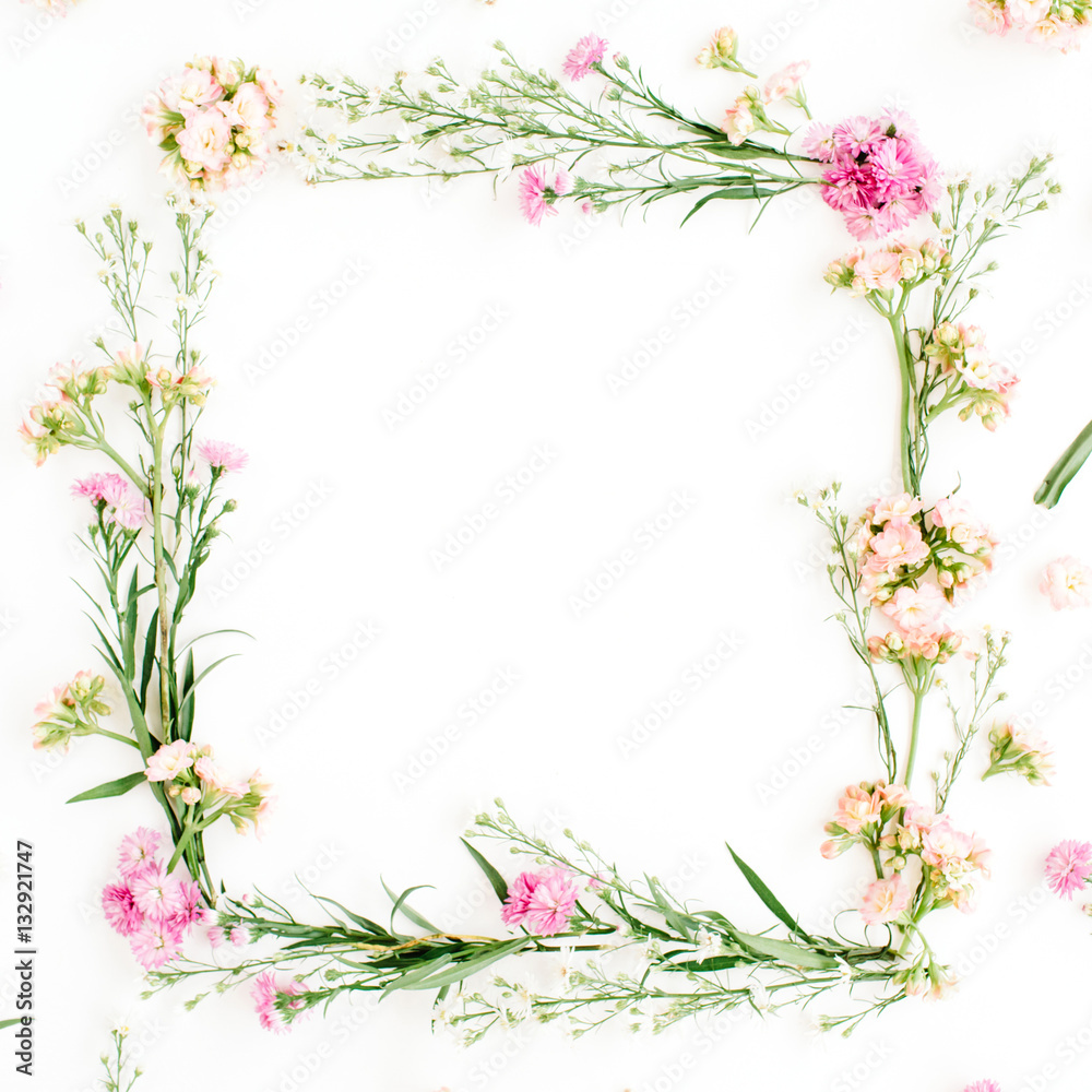 Wreath frame made of pink and beige wildflowers, green leaves, branches on white background. Flat lay, top view. Valentine's background