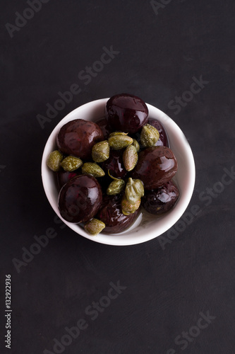 olives and capers on a black background © ytochka89