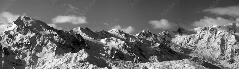 Black and white panoramic view on snowy mountains in sunny day