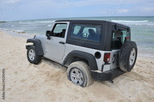A silver off road vehicle stuck in the sand in Cancun, Mexico.