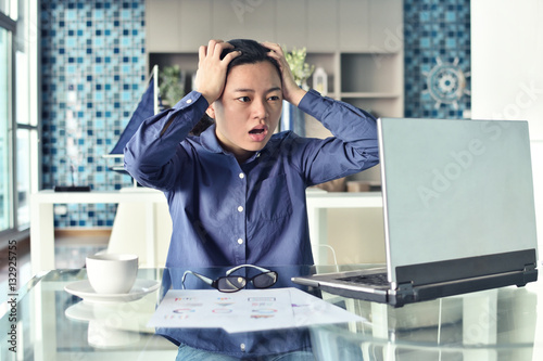 Young Businesswoman sitting with laptop and touching head with s photo