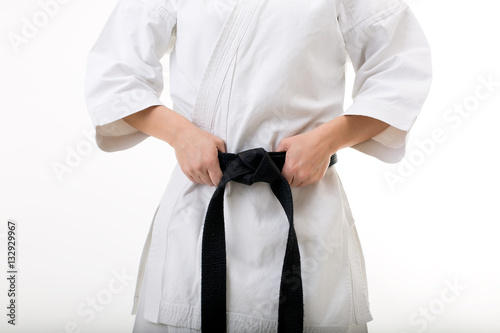 Closeup of female karate fighter hands keeping black belt: studio picture on withe background