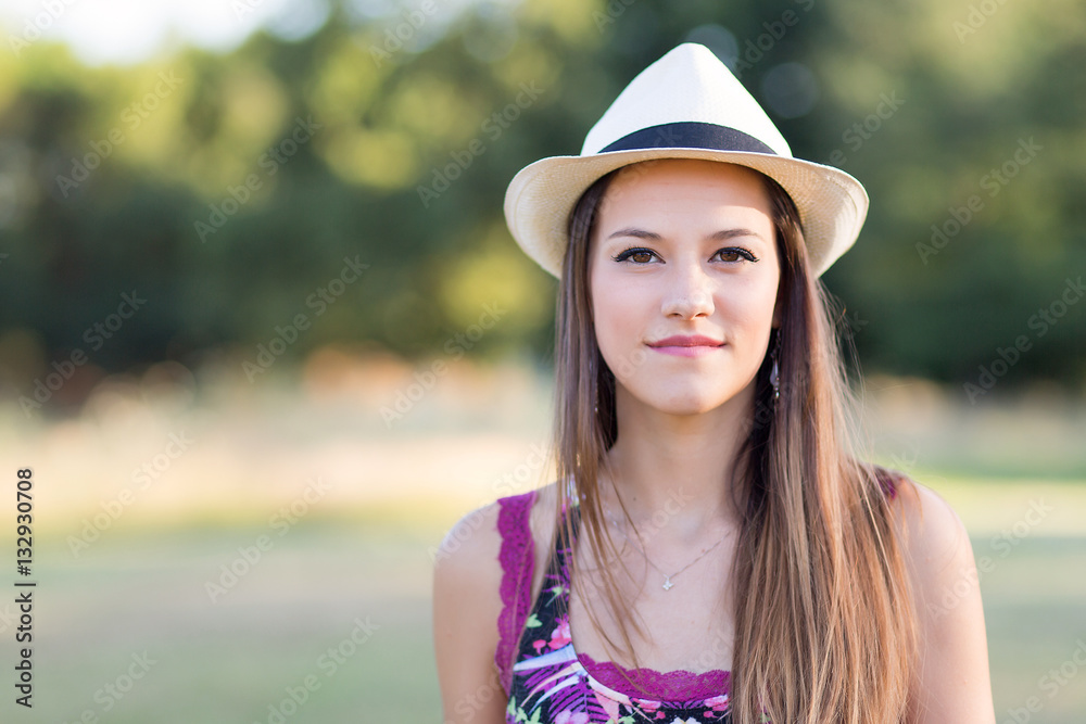 Beauty Romantic Girl Outdoors. Beautiful young brown hair model dressing a white panama hat at park in Sun Light. Summer portrait. Glow Sun, Sunshine.