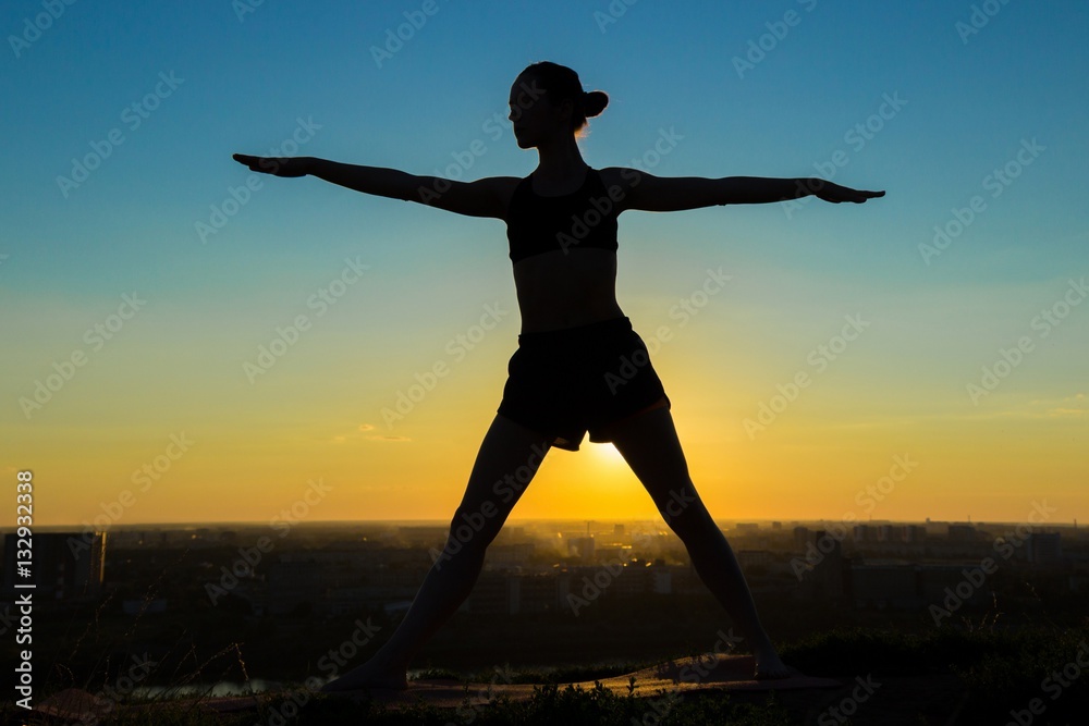 Silhouette of sporty woman doing Ashtanga yoga in the park at sunset. Sunset light, sun lens flares, golden hour. Freedom, health and yoga concept Silhouette of sporty woman doing Ashtanga yoga in the park at sunset. Sunset light, sun lens flares, golden hour. Freedom, health and yoga concept