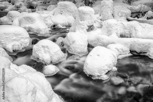 Long exposure of frozen stream in winter forest. Jalovecka valley in Slovakia. Black and white photography photo