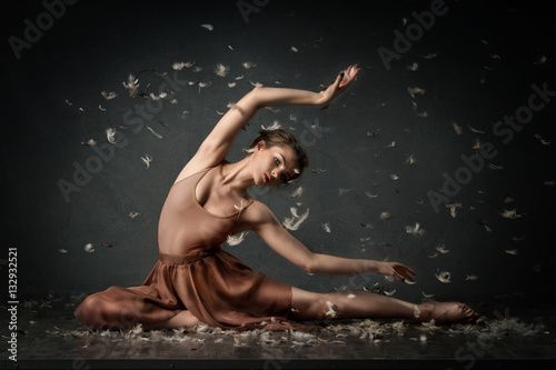 girl dancing barefoot with feathers. ballet. grey background