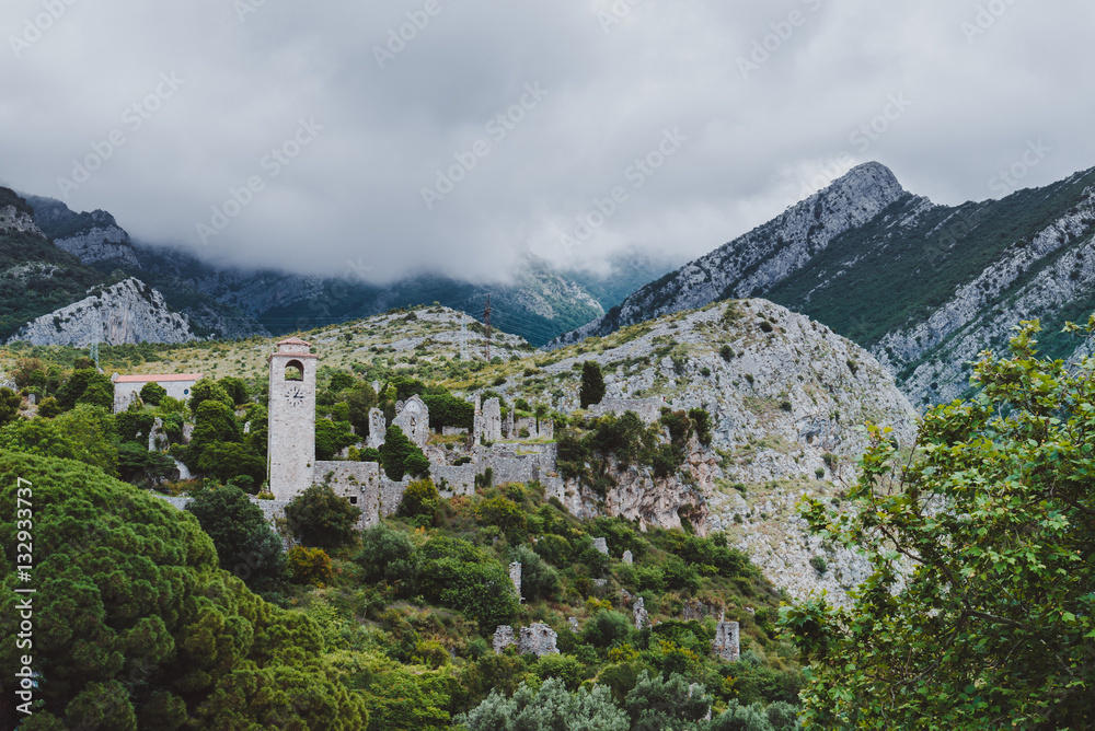 Ancient stone ruins and clock tower at Old Bar town on the cloudy mountains landsape, Montenegro. Stari Bar - ruined medieval city on Adriatic coast, Unesco World Heritage Site.
