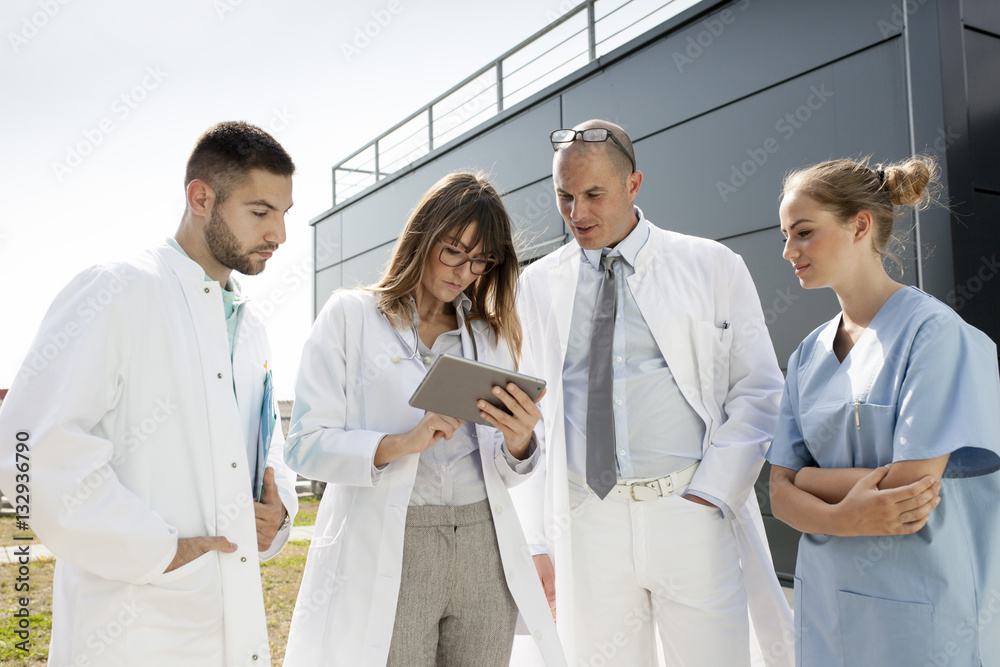 Group of doctors using digital tablet outdoors