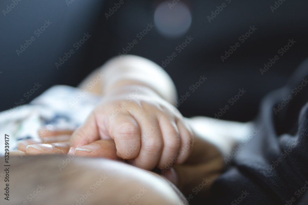 A year old Asian baby holding hand with his mother