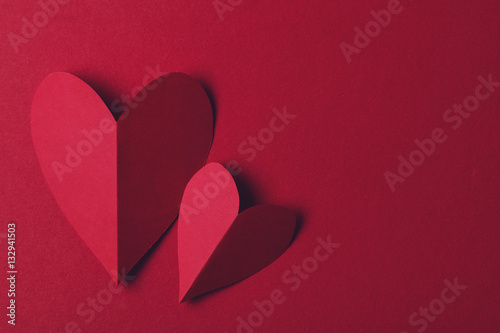 Red paper love heart on a plain red background. Valentines day romance background