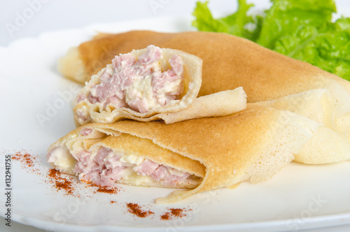 portion of rolled pancakes or crepes cut in half stuffed with ham and cheese on oval dishes served  salad photo