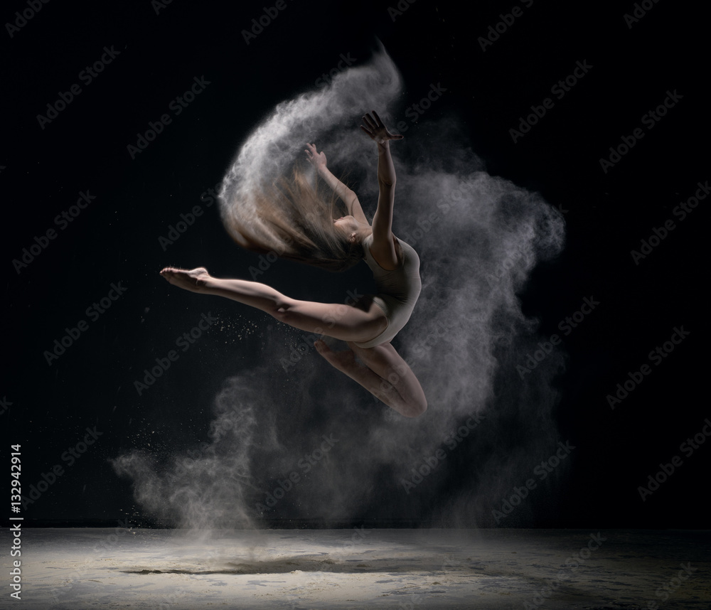 Fototapeta Dziewczyna w ciele skacze w pył chmury czarnym tle