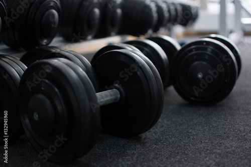 Rows of dumbbells in the gym in the dark colors.
