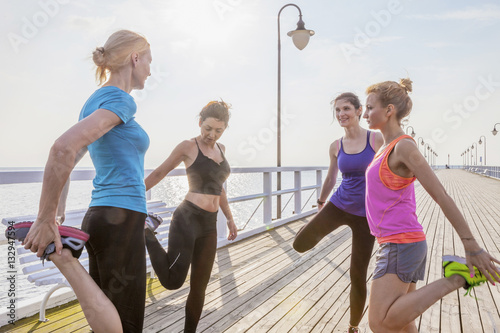 Group of women stretching legs on jetty