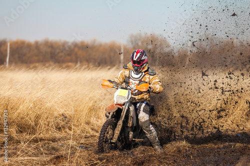 Enduro bike rider on a field with dry grass in autumn. The motor