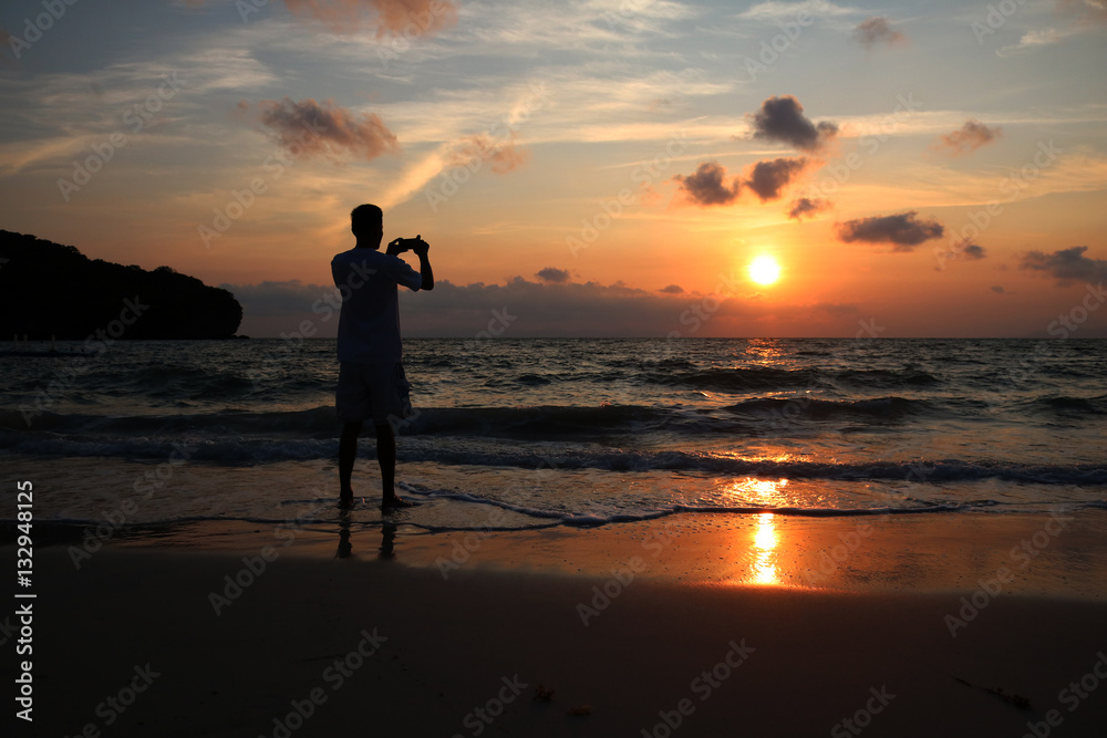 Men use the phone to take pictures of sunrise at ang thong beach. 