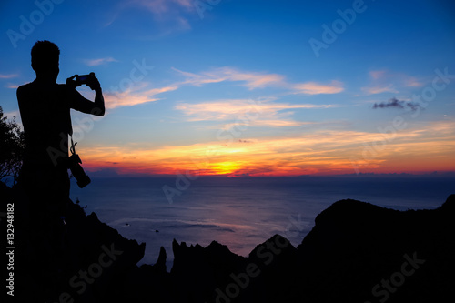 Photographer climbing rock on the mountain with a blue sky sunset 