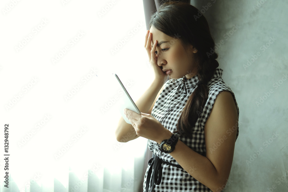 sad emotional portrait of Young pretty business woman work looking on tablet computer in the bright light windows in room office sad emotional portrait of Young pretty business woman work looking on tablet computer in the bright light windows in room office