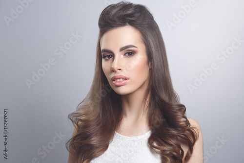 Beauty portrait of a brown-haired sexy girl with elegant hair isolated on gray background.