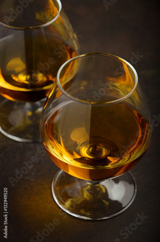 Glass of brandy or cognac on the old rusty background, selective focus, vertical, 