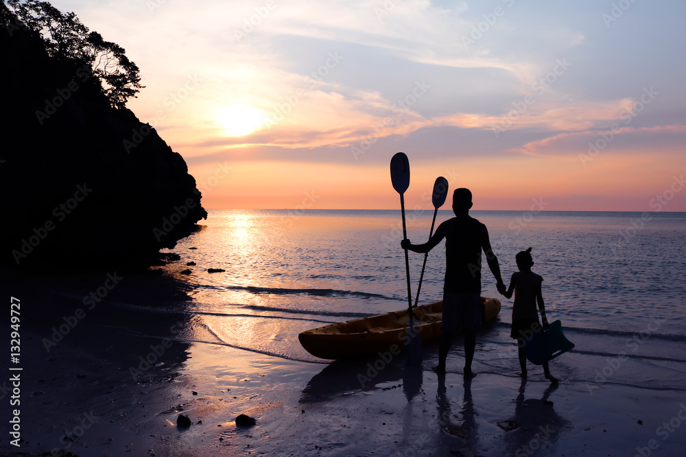 Kayaking on the beach,Man with daughter watching the sunset near the kayak. 