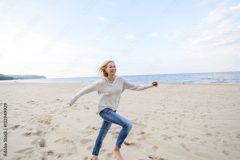 Woman with blond hair running along the beach