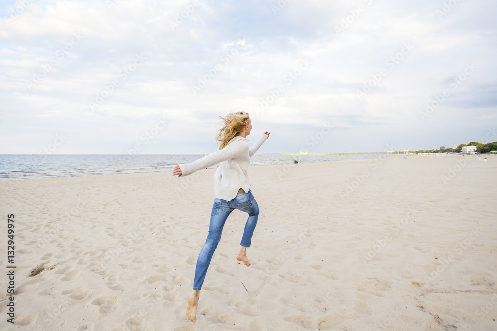 Woman with blond hair running along the beach Woman with blond hair running along the beach