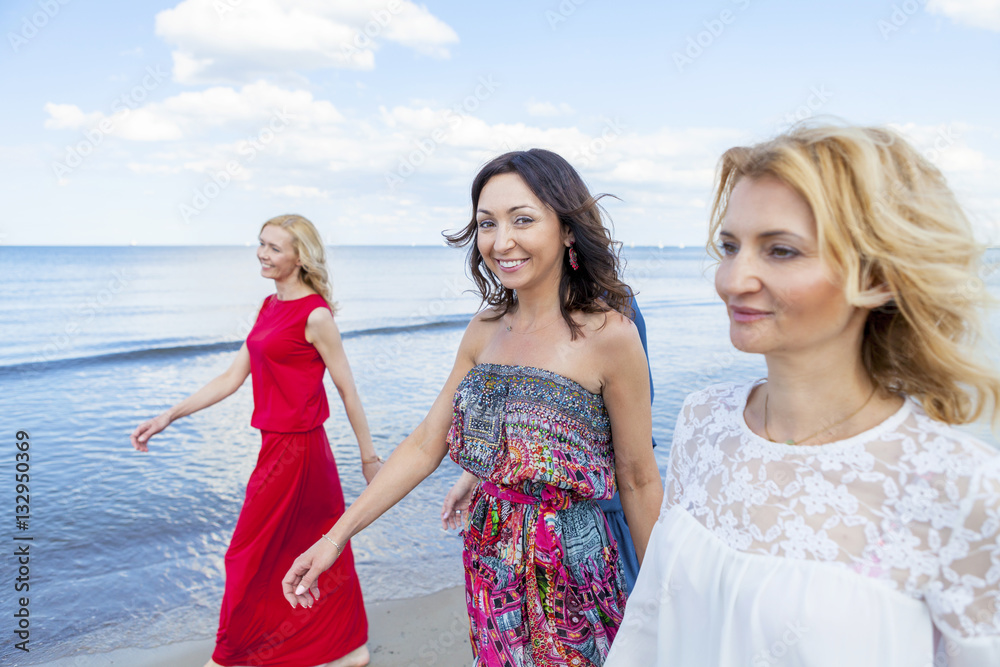 Group of women take a walk along the beach Group of women take a walk along the beach