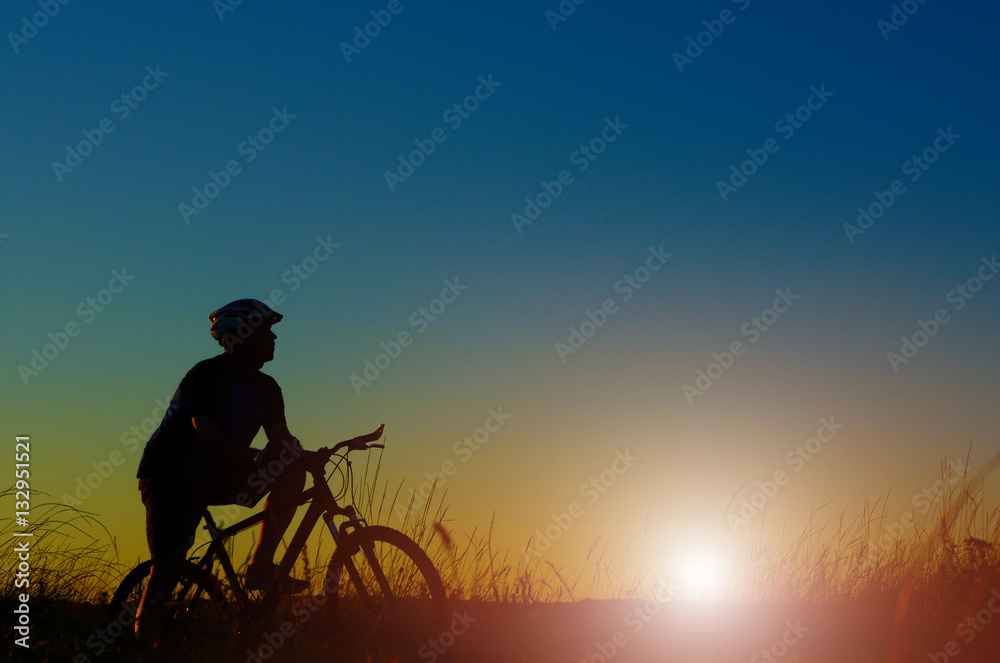 Adult cyclist silhouette having rest dusk time Adult cyclist silhouette having rest dusk time