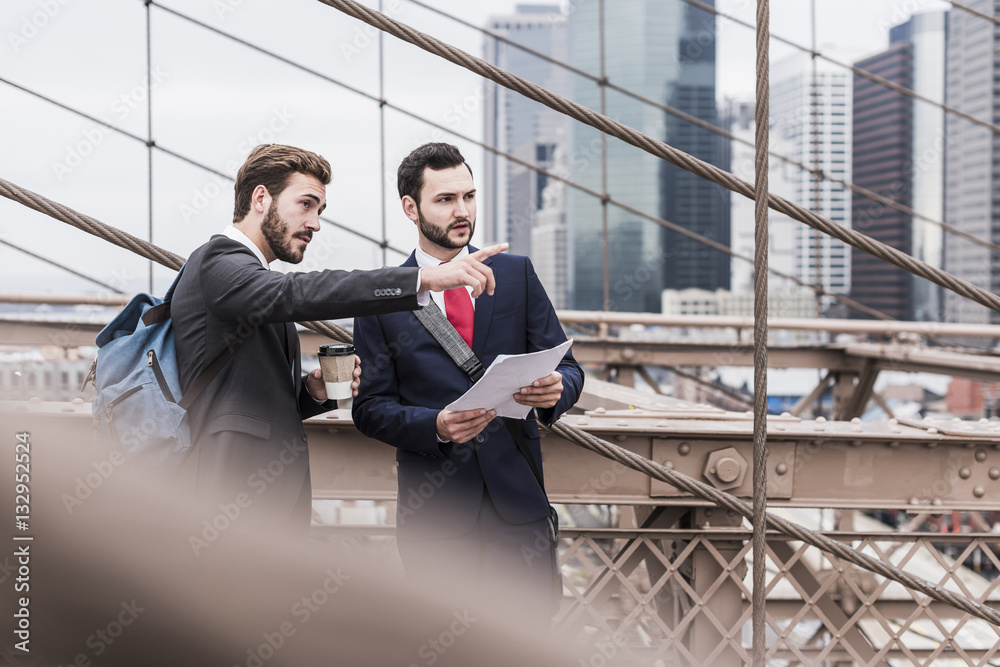 USA, New York City, two businessmen talking on Brooklyn Bridge