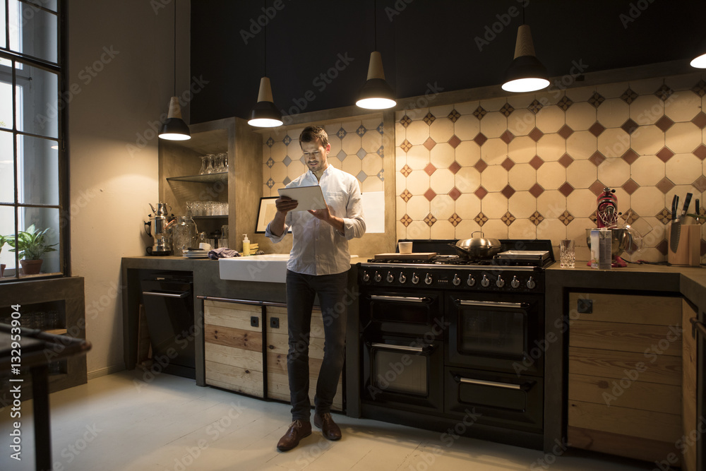 Man standing in the kitchen using tablet Man standing in the kitchen using tablet