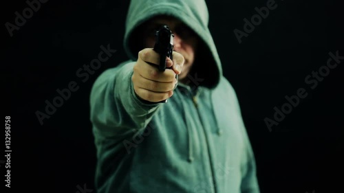 Man in green hoodie cocks and points gun