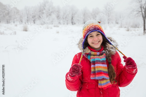 Girl standing in colorful warm clothes on snowy landscape