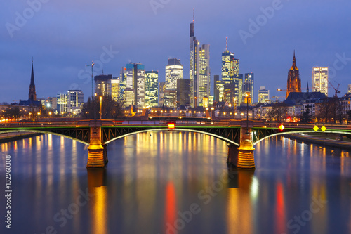 Picturesque view of Frankfurt am Main skyline and Ignatz Bubis Brucke bridge during evening blue hour with mirror reflections in the river  Germany