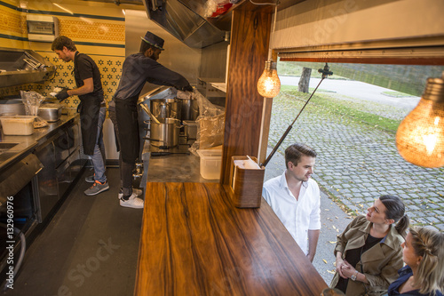 Customers waiting in front of counter of food truck