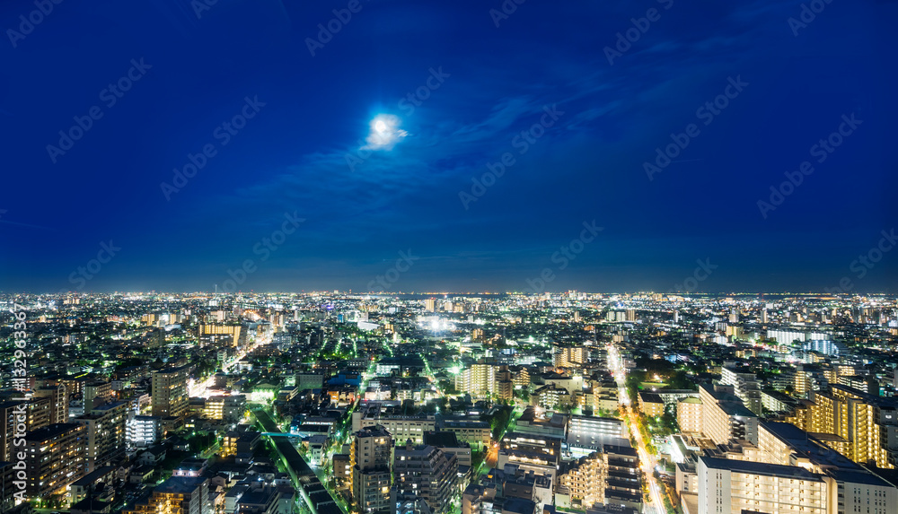 Business and culture concept for real estate and corporate construction - panoramic modern city skyline bird eye aerial night view under dramatic neon glow and beautiful dark blue sky in Tokyo, Japan