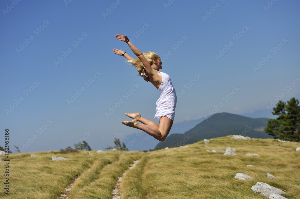 Fototapeta premium No limits. Beautiful young woman in white dress express satisfaction with her nice jump. (she was jumping on trampoline)