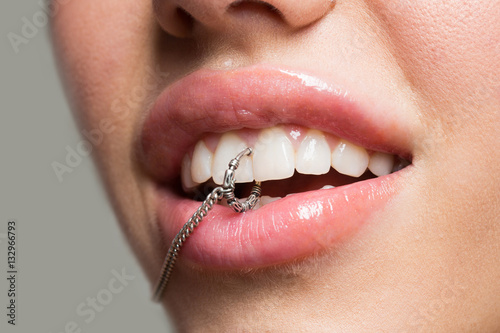 Piercings close up in the mouth of a young girl with full lips, white teeth with natural make-up. Sexy piercing in teeth © Tverdokhlib