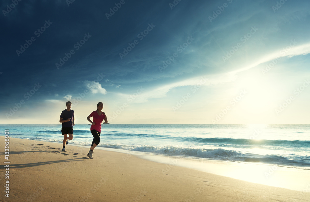 Man and women running on tropical beach at sunset Man and women running on tropical beach at sunset