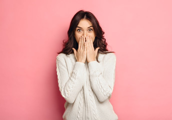 Portrait of amazed young woman over pink background