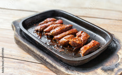 grilled beef tenderloin steak in a hot pan on wooden vintage table