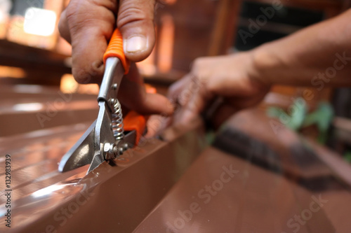 Workers use scissors to cut the metal sheet for roofing.  photo