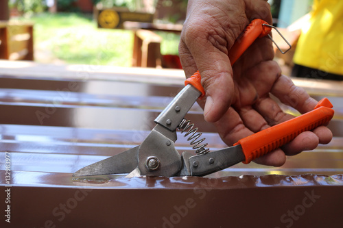 Valokuva Workers use scissors to cut the metal sheet for roofing.