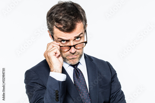 dubious far-sighted businessman holding down eyeglasses looking concerned