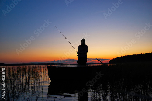 A fisherwoman with a fishing rod standing in boat 