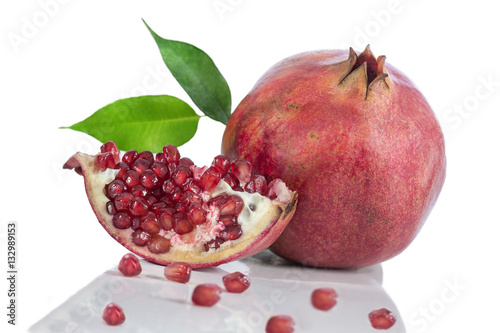 Juicy pomegranate and a slice with leaves. on grey board on a white background.